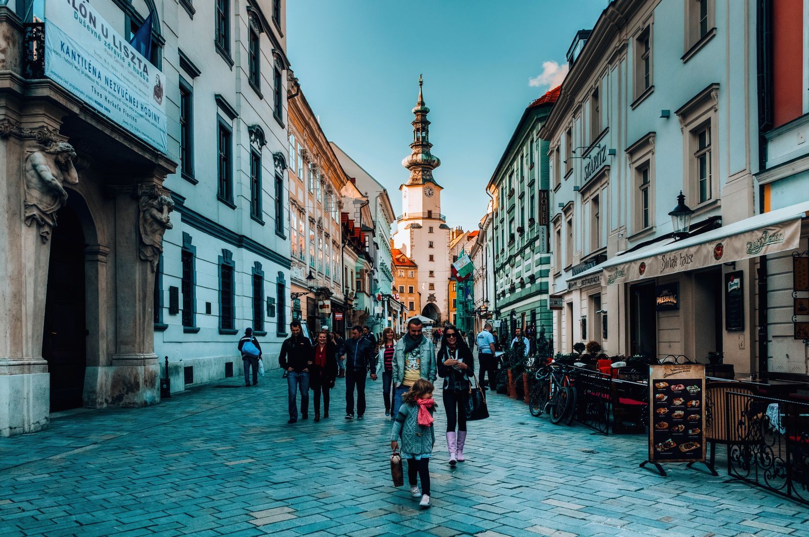 Families walking a cobbled street toward Michael&rsquo;s Gate in Bratislava, a Danube port